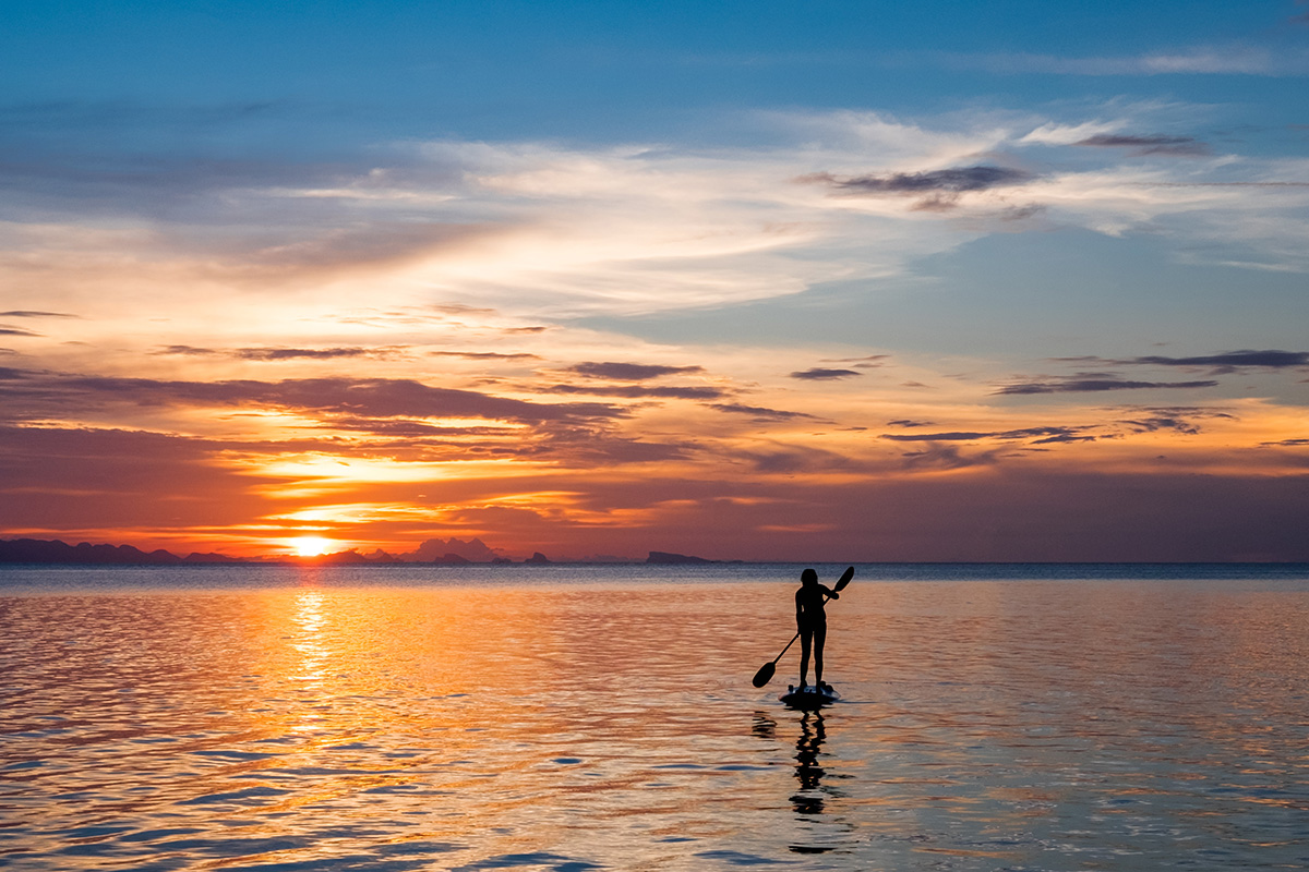 Paddle boarder on water with a sunset